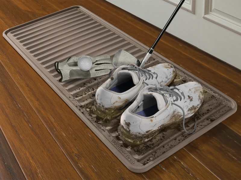 A black waterproof boot tray placed under a compact folding drying rack on a wood floor, catching small water drips from hanging laundry