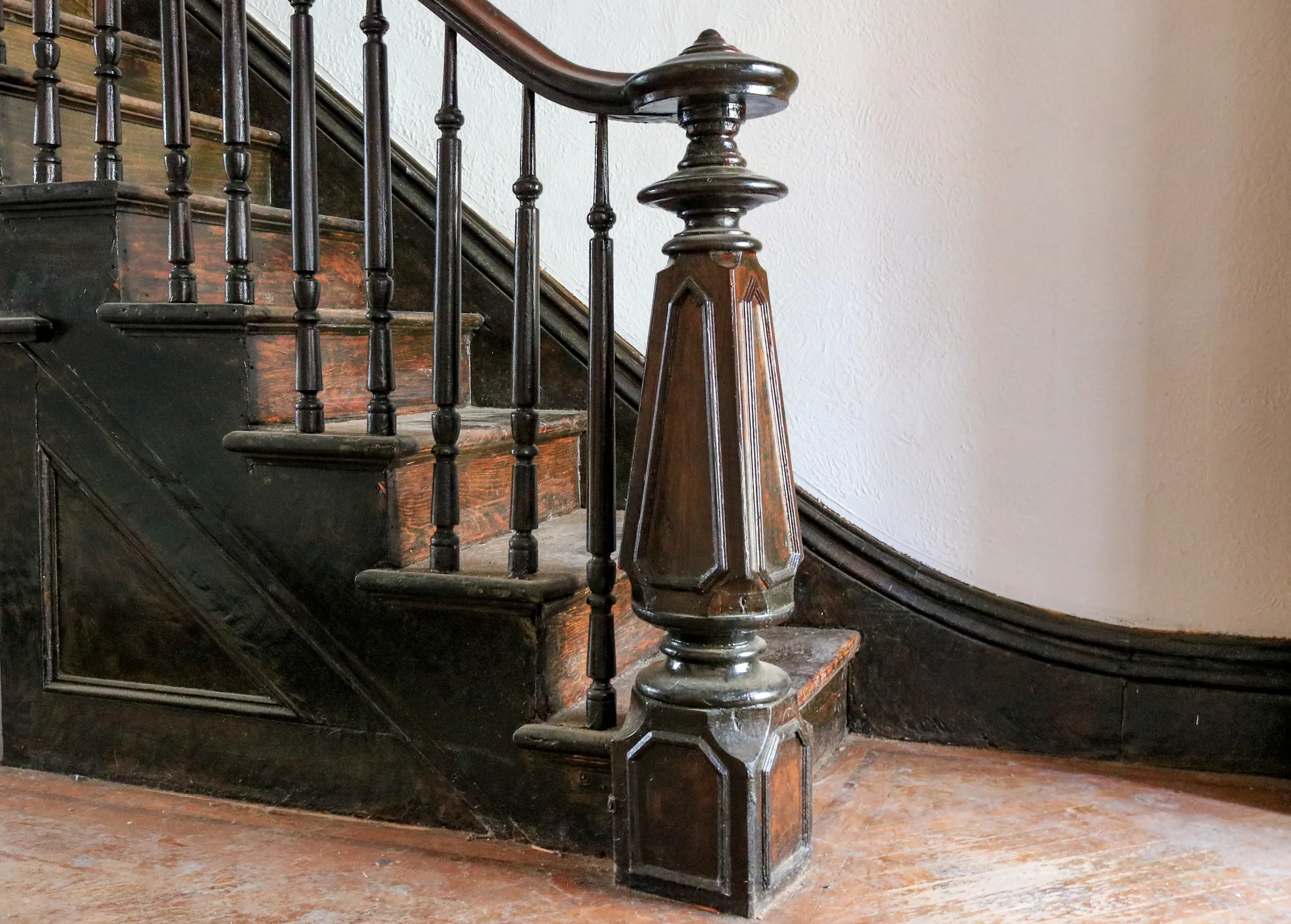 A narrow brownstone stair landing with a tight 90-degree turn and a painted handrail.