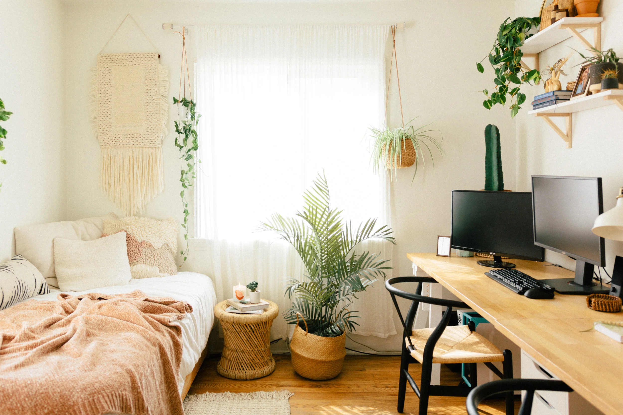 A narrow guest room with a daybed against the longest wall and a small desk set near a window, with a simple chair and minimal decor