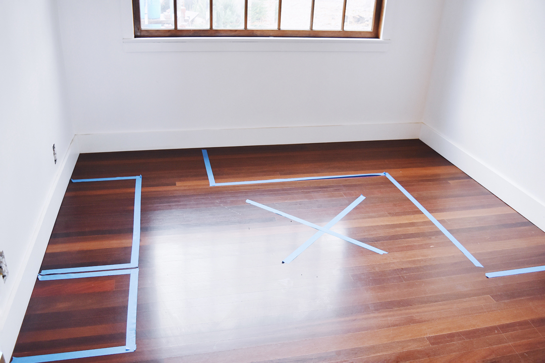 Painter's tape outlining the open footprint of a fold-out sewing table and chair area on a small apartment floor